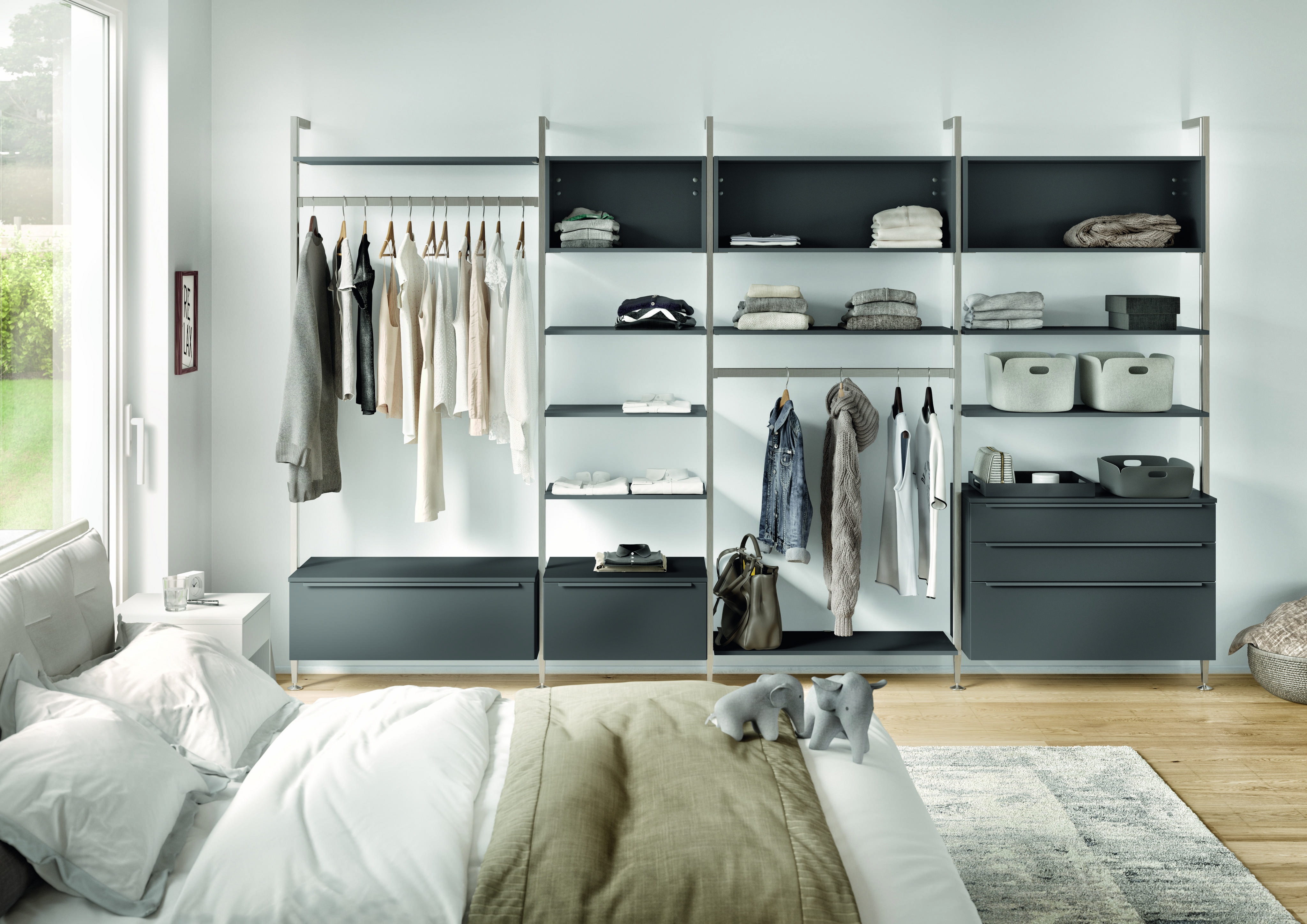 Offener Kleiderschrank mit Kleidung, Boxen und Schubladen neben einem Bett im Schlafzimmer.