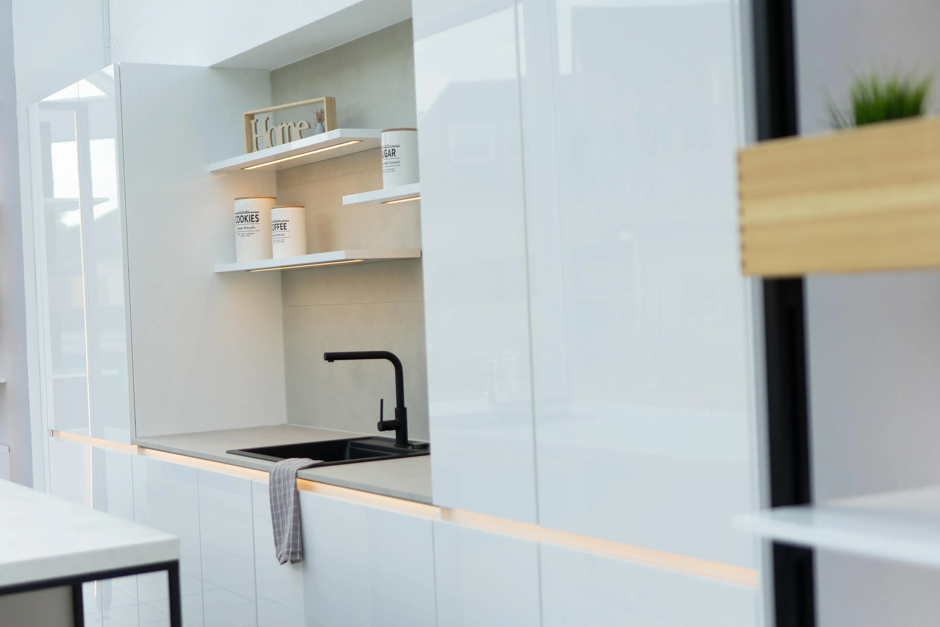 Moderne weiße Küche mit Spüle, offenem Regal und schwarzem Wasserhahn.